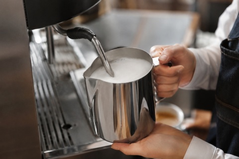 Barista spienia mleko w dzbanku Hendi 451526 900 ml podczas przygotowywania kilku kaw mlecznych